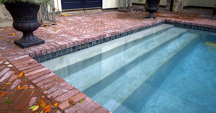 concrete pool with red brick surround