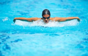 woman with goggles and cap swimming in pool