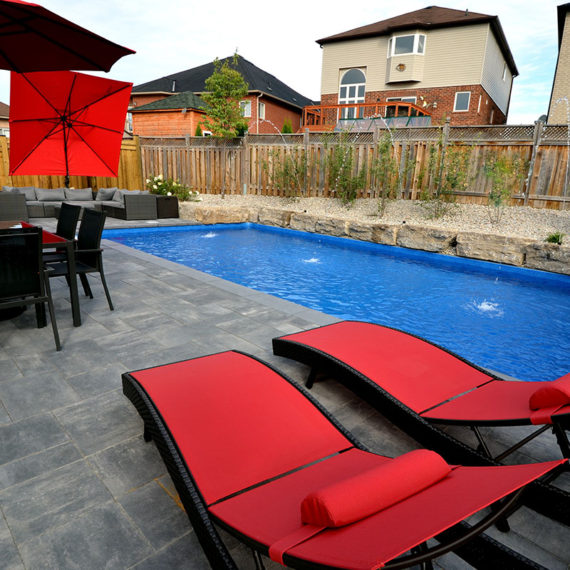 backyard pool with red lounge chairs