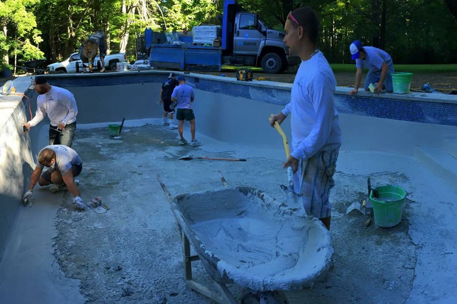 a team of men finishing the concrete in a pool